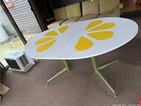 Oval table top with yellow flower petal motifs and white surface.