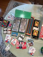 Multiple playing card decks including Red Sox, Carnival, Atari and Aviator brand, a wooden green cribbage board, card shoe, and some boxed decks.