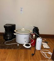 West Bend coffee maker and slow cooker shown with cords on brown carpeted floor against beige wall