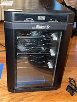 Image of black Danby Maitre D wine chiller fridge with glass door showing interior wire shelves.