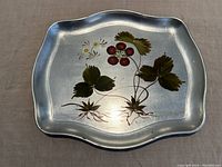 Serving tray showing top surface with hand-painted strawberries, leaves, and flowers on reflective silver background with scalloped edges.