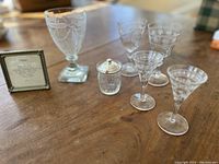 Photo showing all six pieces of the set on a wood surface, including goblet, wine glasses, sherry glasses, and jam jar with silver lid.