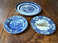 Overview of three historic collectible plates on wooden table: Staffordshire Columbia College, Blue Fitzhugh, J. Hall & Co Waverly Inn