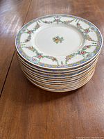 Stack of 12 luncheon plates showing floral B935 pattern with gold trim
