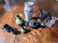All 10 vases arranged on a wooden table showing variety in size, shape, color, and materials including glass and ceramic.