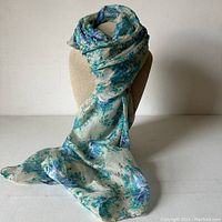 Full view of the silk scarf draped on a mannequin showing the overall floral pattern and size.
