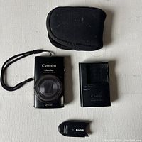 Camera, charger, case, and memory card reader shown on white surface