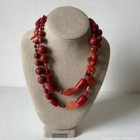 Front view of coral and red jasper bead double necklace displayed on beige bust stand.