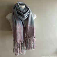 Scarf arranged on mannequin showing full length, draped with soft, pastel multi-colored stripes and fringed ends.