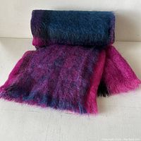 Rolled and partly unrolled mohair wool throw showing colors and texture.