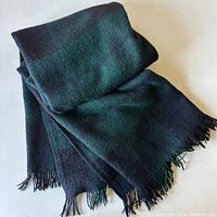 Black watch tartan mohair wool throw folded showing its fringed edges and the fabric texture.