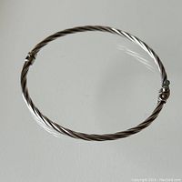 Full view of the twisted sterling silver bangle in circular form showing the overall design and clasp.