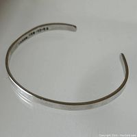 Top view of a narrow sterling silver cuff bracelet showing its shape and polish.