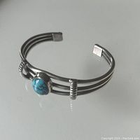 Sterling silver cuff bracelet with turquoise stone on a white background showing side angle and stone details
