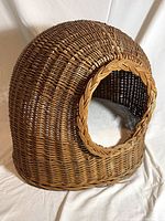 Front angled view of vintage rattan cat dome showing woven texture and circular entrance with braided rim.