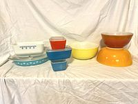 Full view of assorted Pyrex dishes lined up showing variety of colors and shapes