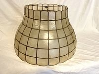 Front side view of lampshade showing the scalloped shape and pearl-like Capiz shell panels framed in metal.
