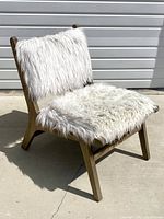 Side angled view showing wood frame with white faux fur seat and backrest outdoors on concrete surface