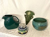 Overview of four pottery items including Fiesta pitcher, Dupuis wall pocket, hand-painted jar with lid, and Roseville bowl
