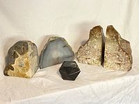 Group photo showing two pairs of stone bookends and a black marble geometric paperweight in the center, displayed on a white cloth background.
