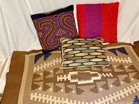 Lot overview showing three pillows and small tribal rug/throw with neutral geometric patterns