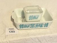 Overall view of both dishes stacked, showing the blue Amish rooster and farmer design on white opaque glass.