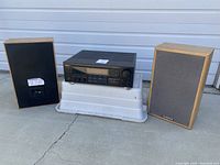 Full front view of receiver on stand with left and right speakers on either side