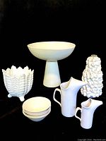 Full lot of white ceramic pottery pieces grouped together on black background for overall view.