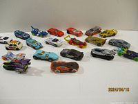 Lot of 20 assorted Hot Wheels toy cars in various colors and designs, displayed on a flat surface.