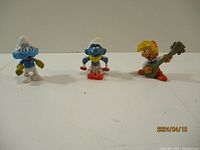 Three Smurf figurines together: Peewit with lute, skiing Smurf, classic Smurf