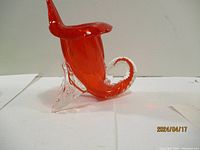 Side view of red art glass octopus figurine showing curled tentacle and clear glass base