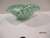 Side angle view of the green and white art glass bowl showing the ruffled edges and floral millefiori pattern.