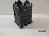 Front and side view showing the detailed floral and scrollwork design on the cast iron bank.