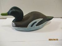 Front and side views of a wooden duck decoy painted with green, black, gray, blue and white, showing minor wear marks on neck area.