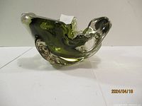 Side view of signed green glass bowl displaying organic flowing form and color variations.