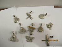 10 various metal clip on ornaments laid on white surface. Shapes include butterflies, dragonflies, and scallop shells.