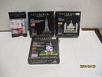 Four boxed Nanoblock sets displayed on white surface. Includes architectural models and smaller set.