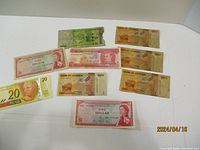 Photo showing a collection of 10 old banknotes from various countries including Uganda, Caribbean, and Brazil in good condition.