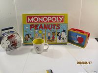 Full display of Peanuts Monopoly board game, two lunch pails, and ceramic mug on white background.