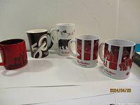 Five Tim Horton mugs arranged in a row showing different designs and colors on upper surface.