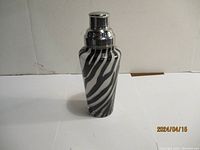 Photo of vintage cocktail shaker with a black and white zebra stripe pattern, closed with top cap on.