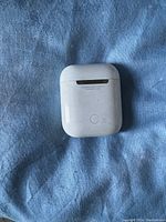 Top view of the AirPods charging case showing front button and scuffed surface