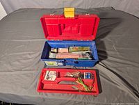 Large blue and red tackle box open showing red tray with fishing lures and hooks