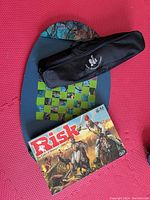 Photo of Risk board game box, black chess set carrying case, and handmade oval chess board with checkered pattern
