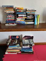 Additional photo showing more books, graphic novels, and DVDs spread on a table surface to highlight quantity and condition.