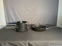 Stack of five Calphalon frying pans of various sizes shown from side angle.