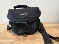 Closed black Promaster camera carrying case on wooden surface.