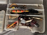 Open tackle box showing assorted fishing lures including crankbaits, spinnerbaits, and jig heads