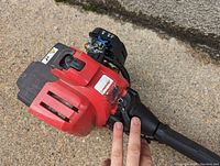 Close-up photo of the red Troy-Bilt leaf blower showing the engine housing, control handle, and ports.