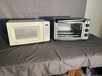 Both microwave and convection toaster oven shown side by side on a table with black cloth covering.